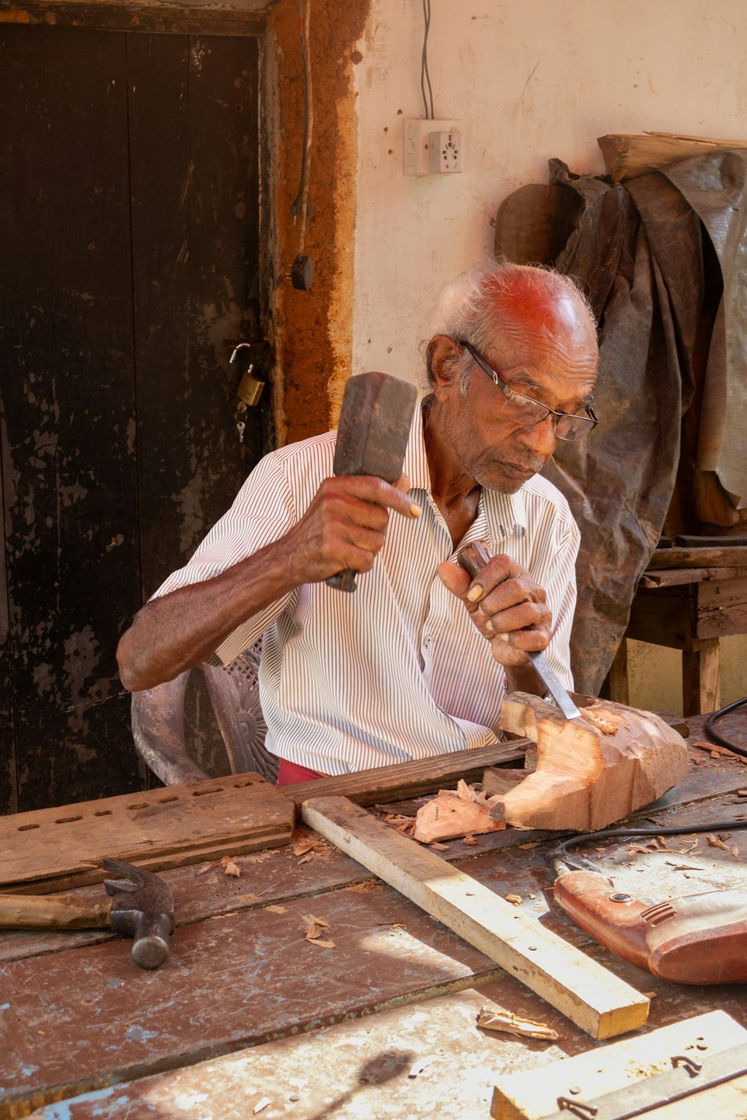 Senior craftsman carving wood with hammer and chisel
