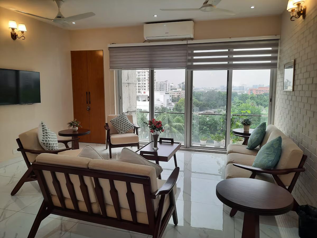 Living room with timber armchairs and tall windows onto trees