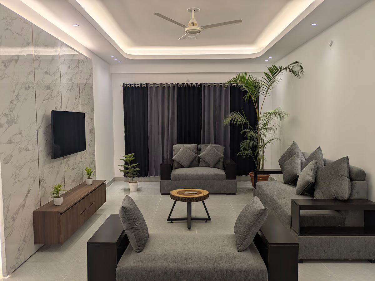 Living room with grey sofas, plants and a lit ceiling cove