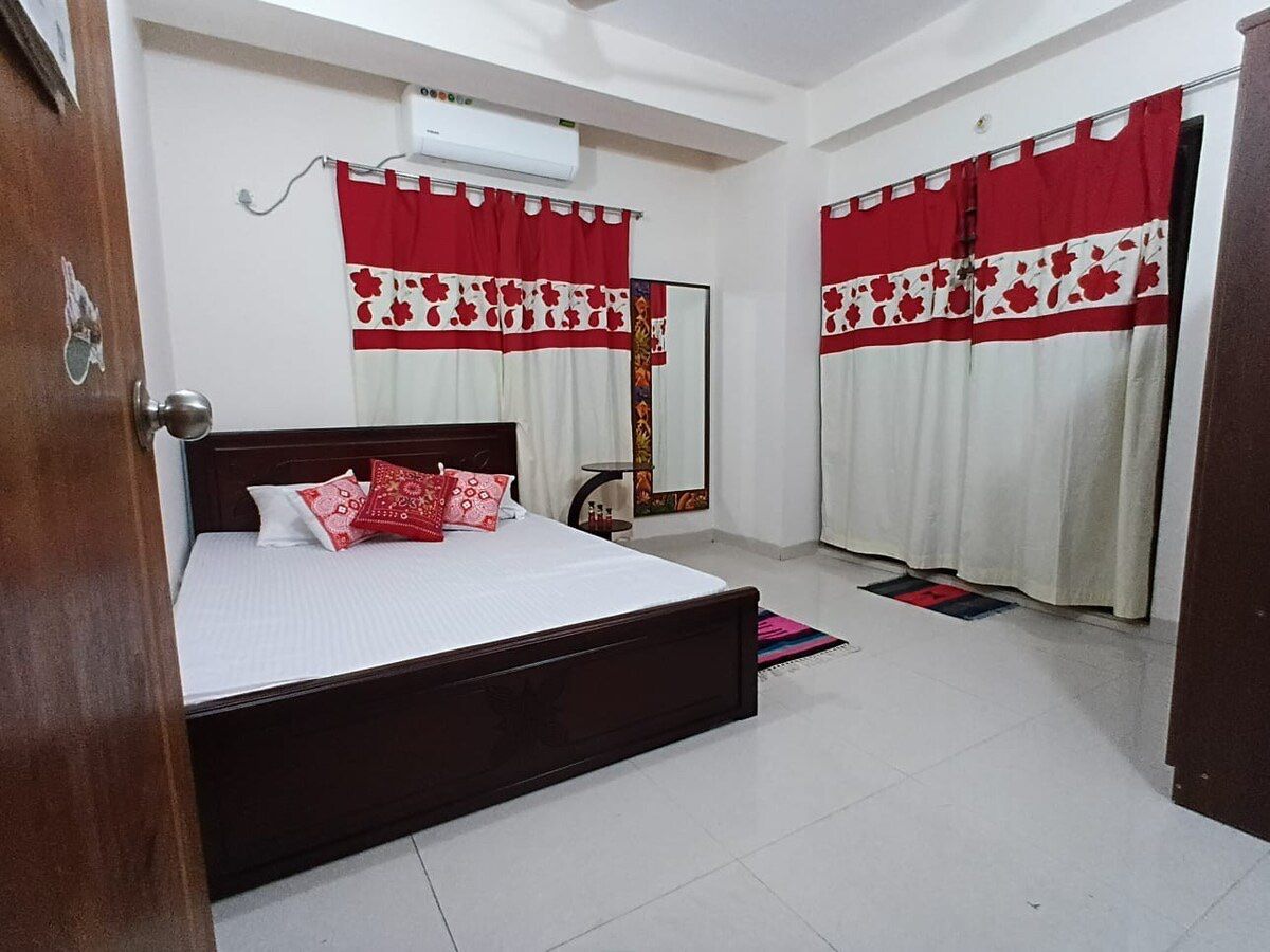 Bedroom with red-and-cream printed curtains and timber bed